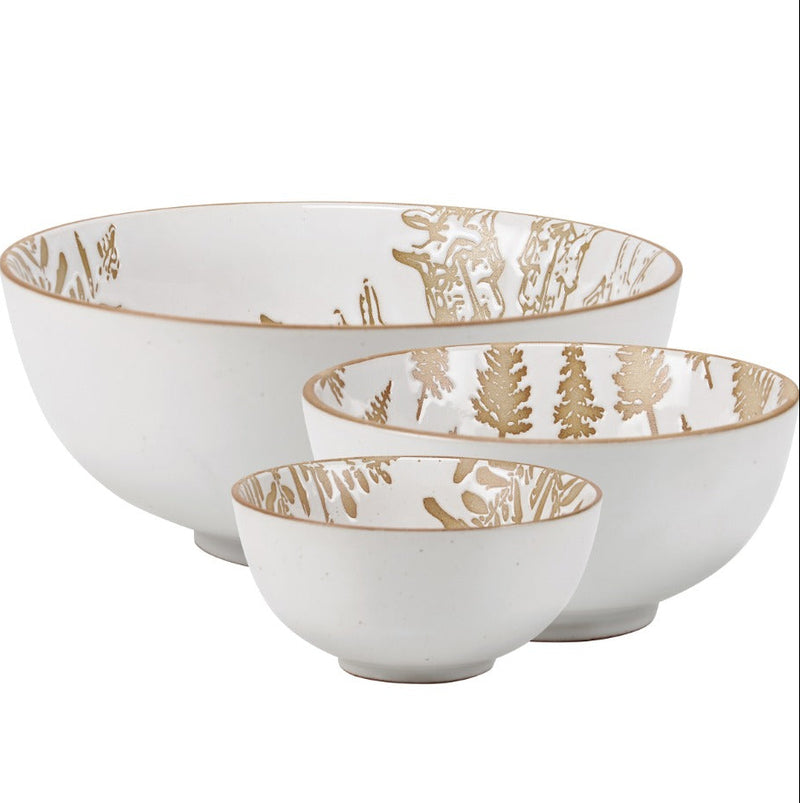 A set of three stoneware bowls with a snowy cream hue and nature-themed designs, including snowflakes and a winter tree, with glossy finishes.